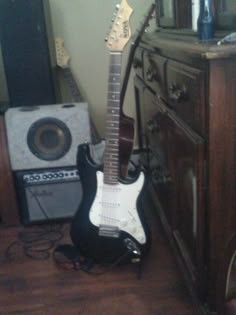 an electric guitar sitting on the floor in front of a cabinet and amp with other musical equipment