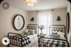 two twin beds in a bedroom with white walls and black metal frame bed frames, green throw pillows on them