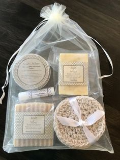 a bag with some soaps and other items in it sitting on a table next to a white ribbon