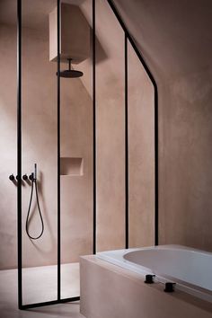 a bathroom with a bathtub, shower head and shelves on the wall next to it