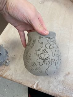 a hand is touching a vase on a table