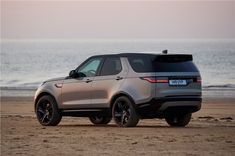 a silver range rover parked on the beach near the ocean with its hood up and roof down