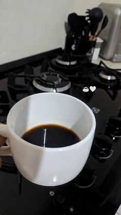 a cup of coffee sitting on top of a stove