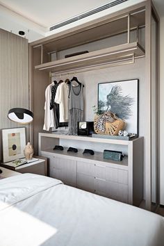 a bedroom with an open closet and clothes hanging on the wall next to a bed