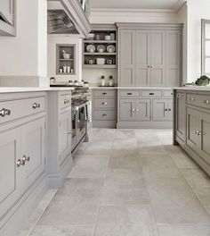 a large kitchen with gray cabinets and white counter tops, along with marble flooring