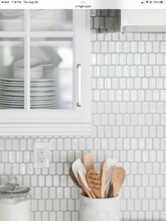 a kitchen with white tiles and wooden utensils