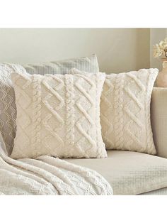 two white pillows sitting on top of a couch next to a vase filled with flowers