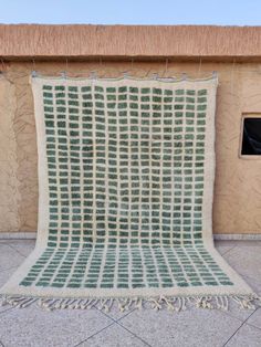 a green and white blanket sitting on top of a cement floor next to a window