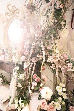 an arrangement of flowers and greenery in front of a mirror