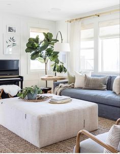 a living room filled with furniture and a piano in front of a window covered in plants