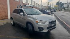 a silver car parked in front of a brick building on the side of a road