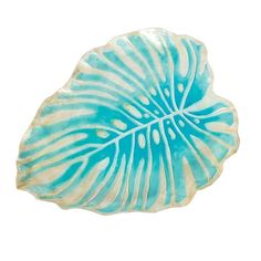 a blue and white leaf shaped dish on a white background