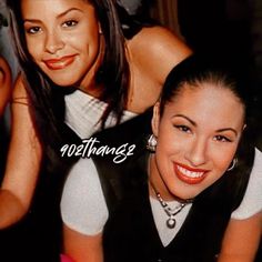 two women are smiling for the camera and one is wearing a white shirt with black sleeves