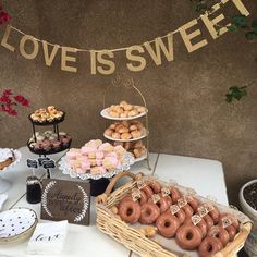 a table topped with lots of donuts next to a sign that says love is sweet