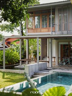 a house with a bike parked in front of it and some plants around the pool