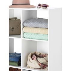 a white shelf filled with lots of folded clothes and a hat on top of it