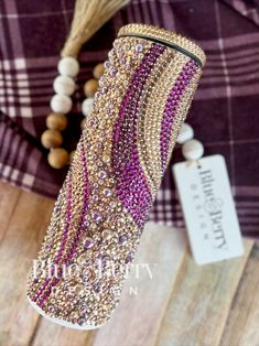 a purple and gold beaded vase sitting on top of a wooden table next to a string of beads