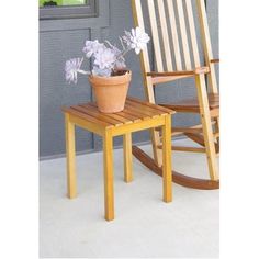 a wooden rocking chair next to a potted plant