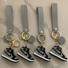 four air jordan keychains are shown on a marble surface with gold - plated metal rings