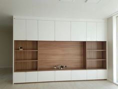 an empty room with white cabinets and wooden shelves