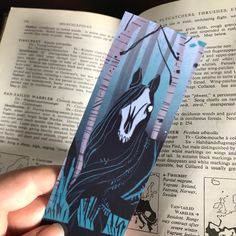 someone is holding up a bookmark with an image of a horse