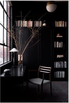 a chair and table in front of a window with bookshelves on either side