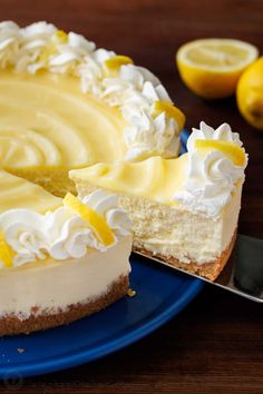 a cheesecake on a blue plate with a slice missing from it and two lemons in the background