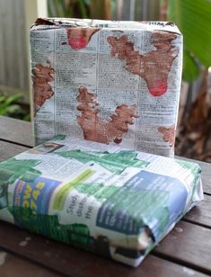 an open book sitting on top of a wooden table next to a bag with newspaper covering it