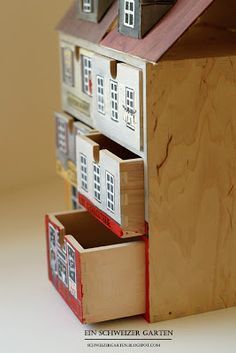 a toy house made out of wood with several windows and shutters on each side