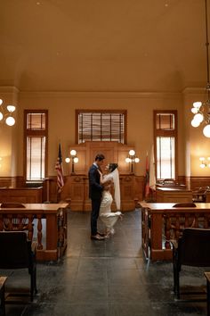 a bride and groom standing in the middle of a room filled with wooden desks