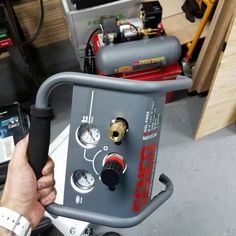 a person holding a machine in their hand and some tools on the table behind them