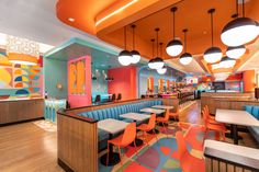 the interior of a restaurant with brightly colored booths and colorful lights hanging from the ceiling