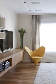 a bedroom with a bed, television and chair in it's corner next to a window