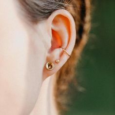 a close up of a person's ear with two small gold studs on it