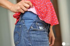 a woman is showing off her jeans with the back pocket open and there are hearts on it