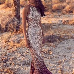 a woman standing in the desert wearing a dress with sequins