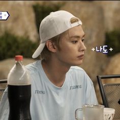 a young man sitting at a table with a bottle of water in front of him