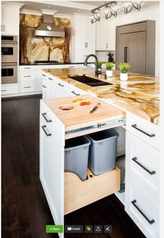 a kitchen with white cabinets and an island in the middle that has two trash cans on it