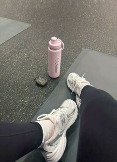 a person's feet resting on a mat next to a pink water bottle