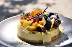 a white plate topped with a cheesecake covered in lots of different types of fruit