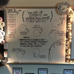 a white board with writing on it in front of a wall mounted clock and lights