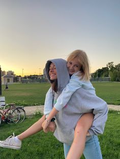 two women are holding each other in the grass