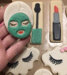 a hand holding a cookie decorated with fake eyelashes and makeup on it's face