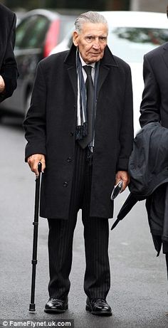 two men in suits and ties are walking down the street with umbrellas on their heads