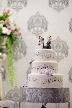 a wedding cake decorated with music notes and bride and groom figurines on top