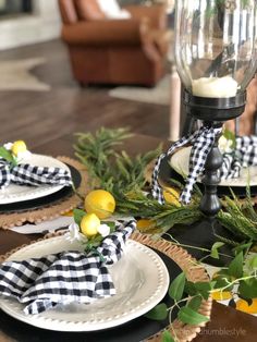 the table is set with black and white plates, plaid napkins and lemons