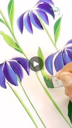 someone is painting purple flowers with green leaves