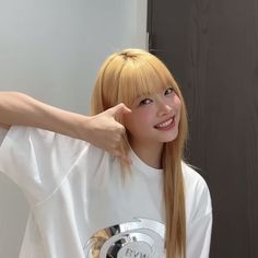 a woman with long blonde hair wearing a white t - shirt and posing for the camera