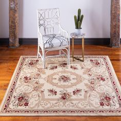 a white chair sitting on top of a wooden floor next to a table with a potted plant