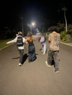 three people are running down the street at night with one person holding his arms out